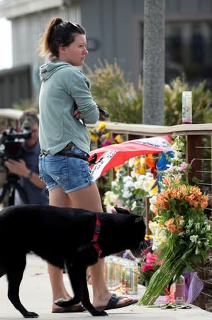 A woman and her dog pause to look over a makeshift memorial near Truth Aquatics as the search continues for those missing in a pre-dawn fire that sank a commercial diving boat near Santa Barbara, California