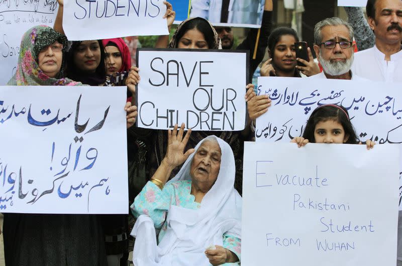 Family members hold signs demanding the evacuation of Pakistani students from Wuhan city, during a protest in Karachi