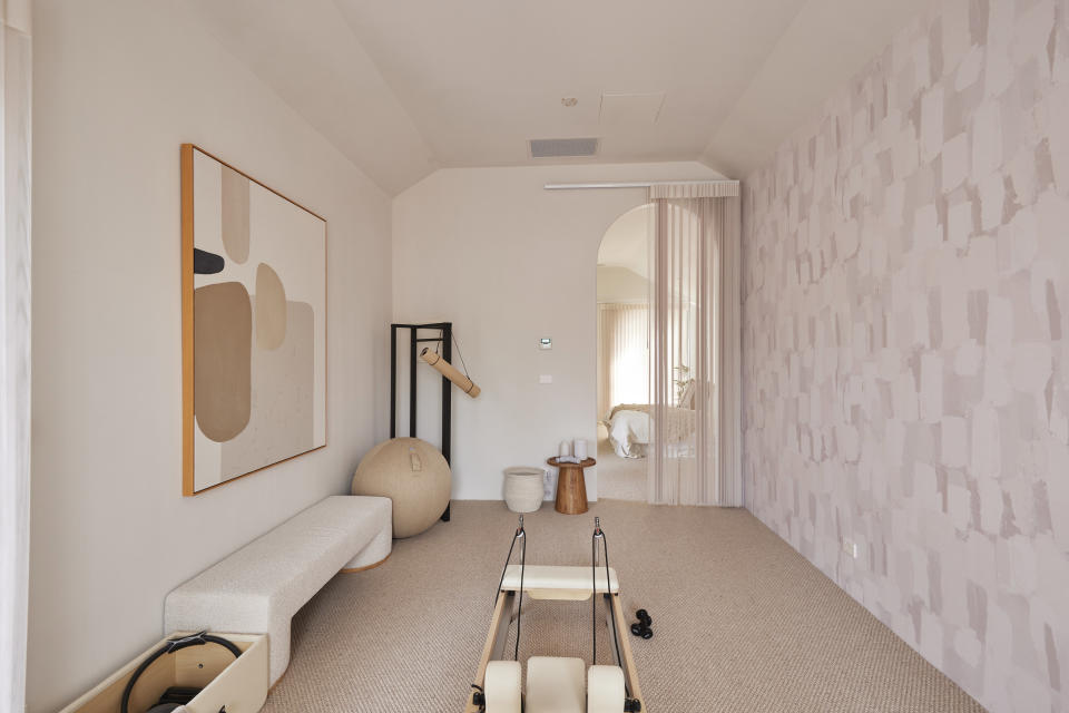 A cream coloured pilates studio, with other exercise equipment along the left wall. 