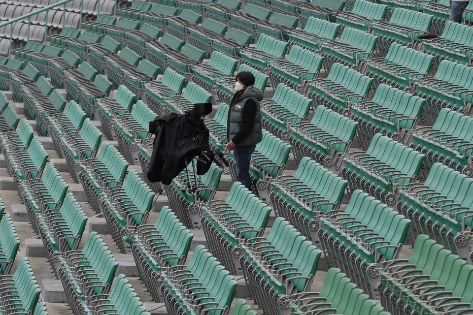 A TV camera man works near empty seats before the start of a baseball game between Hanwha Eagles and SK Wyverns in Incheon, South Korea, Tuesday, May 5, 2020. Cheerleaders danced beneath rows of empty seats and umpires wore protective masks as a new baseball season began in South Korea. After a weeks-long delay because of the coronavirus pandemic, a hushed atmosphere allowed for sounds like the ball hitting the catcher's mitt and bats smacking the ball for a single or double to echo around the stadium. (AP Photo/Lee Jin-man)
