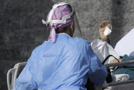 A patient waves to her relative as she is carried inside the first aid area of the Cardarelli hospital in Naples, Italy, Friday, Nov. 13, 2020. Italian Government and health officials were analyzing data to see if the hard-strapped Campania region, which includes Naples, should be declared a red-zone. (AP Photo/Gregorio Borgia)