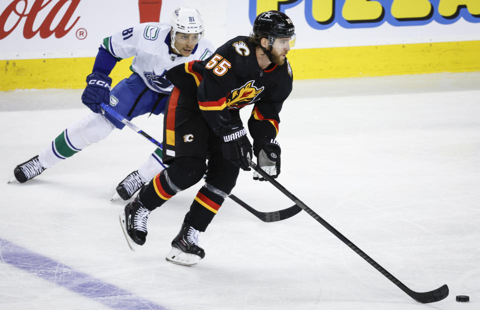 Vancouver Canucks forward Dakota Joshua, left, chases Calgary Flames defenseman Noah Hanifin during the second period of an NHL hockey game, Saturday, Dec. 2, 2023 in Calgary, Alberta. (Jeff McIntosh/The Canadian Press via AP)