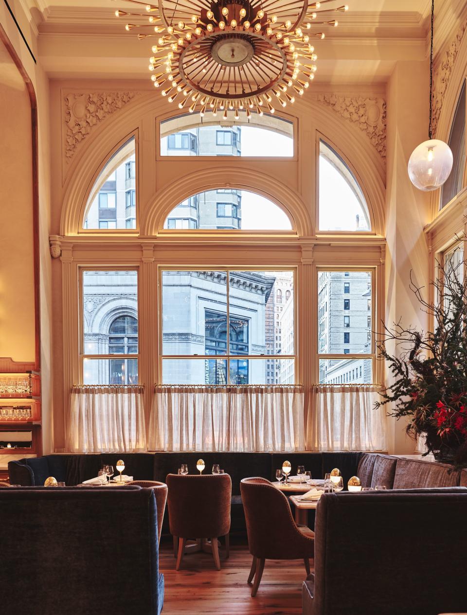 Opulent brass chandeliers offset the natural light that floods the dining room, while curvilinear mohair seating adds sex appeal.