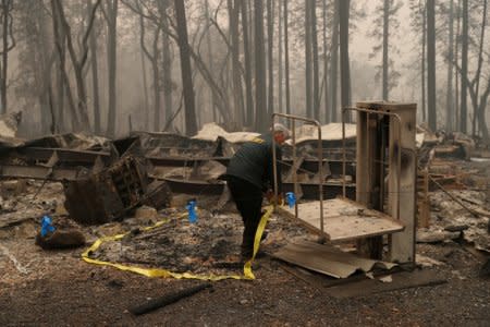 FILE PHOTO: A Butte County Sheriff deputy places yellow tape at the scene where human remains were found during the Camp fire in Paradise, California, U.S. November 10, 2018. REUTERS/Stephen Lam/File Photo