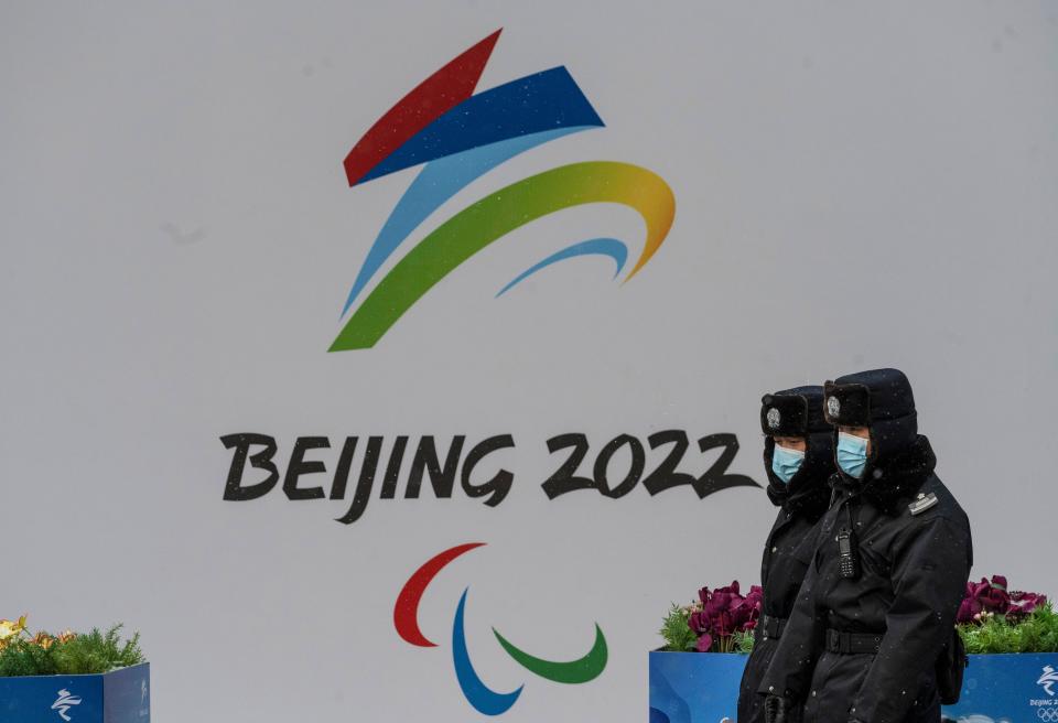 Security walk by a billboard for the Beijing 2022 Winter Olympics and Paralympics during a snowfall on January 20, 2022 in Beijing, China.