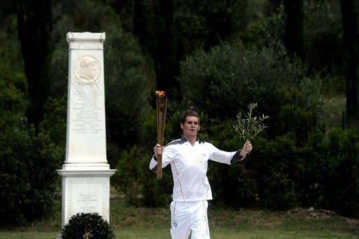 The first torch bearer, swimmer Spyros Gianniotis, runs with the Olympic flame during the lighting ceremony at Olympia, Greece, on May 10. The Olympic flame was lit in Ancient Olympia in Greece on Thursday, in a solemn ceremony filled with mystery and tradition that signals the final countdown to the start of this year's summer Games in London