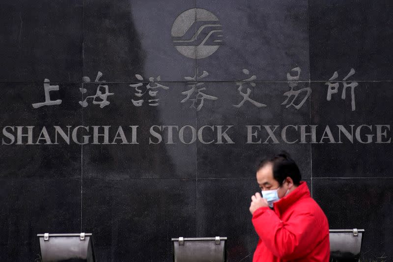 FILE PHOTO: A man wearing a mask walk at the Shanghai Stock Exchange building at the Pudong financial district in Shanghai
