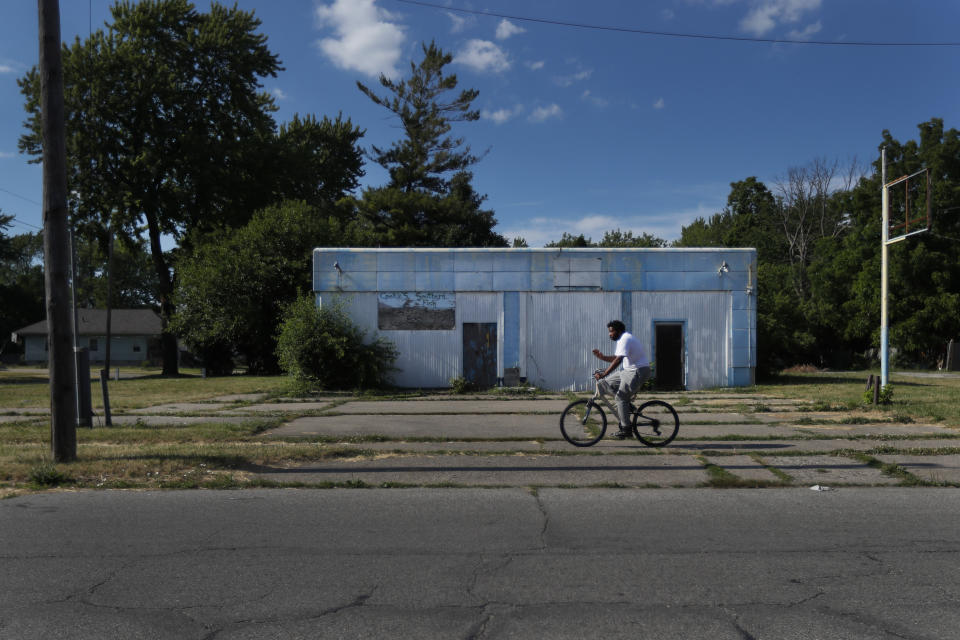 A man rides his bicycle past an abandoned service station in the impoverished east side neighborhood of Saginaw, Mich., on Monday, June 29, 2020. It's difficult to celebrate America in Saginaw this July 4th. The deadly pandemic kept families apart. A brutal recession means money is tight. Weeks of protest over racial inequality left many debating what exactly should be celebrated and what must be changed. (AP Photo/Charles Rex Arbogast)