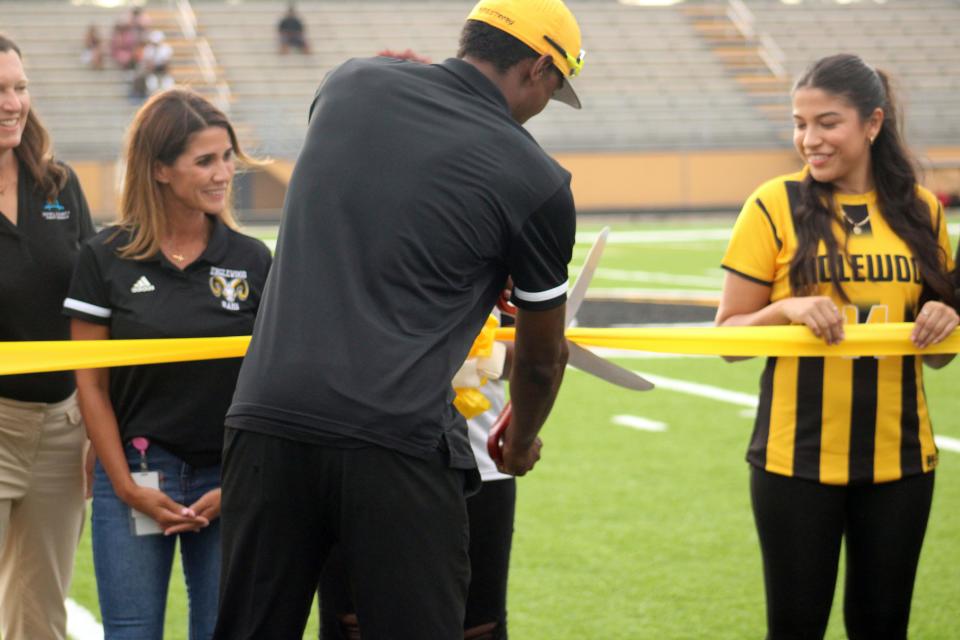 Englewood head coach Kevin Johnson cuts the ribbon on the new field before Friday's high school football game against Ed White.