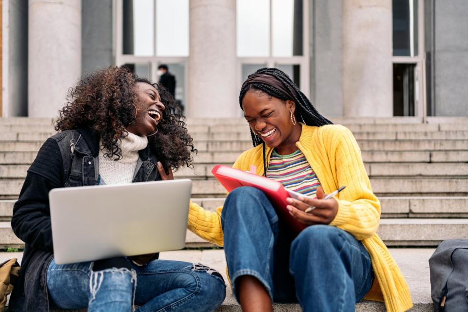 Two Black women laughing on steps.