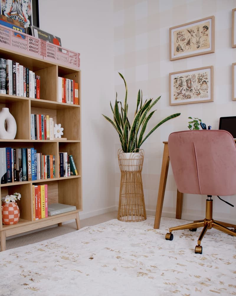 office with beige and white gingham walls, wood desk, and gray sofa