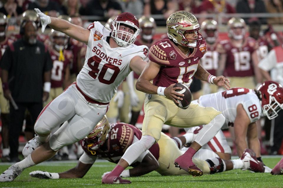 Florida State quarterback Jordan Travis (13) scrambles away from Oklahoma defensive lineman Ethan Downs (40) during the first half of the Cheez-It Bowl on Dec. 29, 2022, in Orlando, Fla.