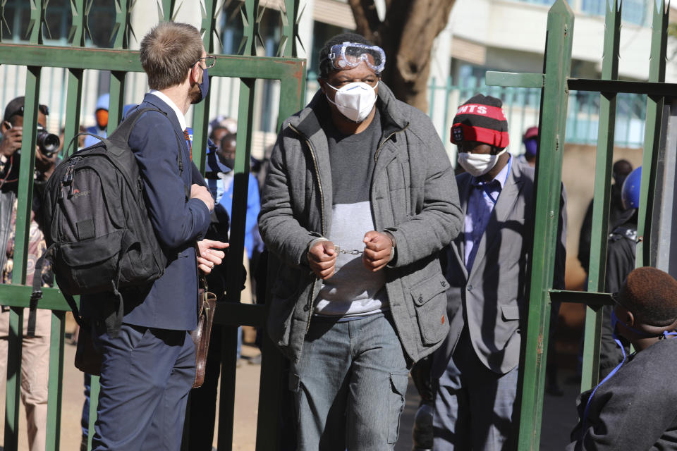 Zimbabwe journalist Hopewell Chin'ono appears at the magistrates courts while handcuffed in Harare, Wednesday, July, 22, 2020. Chin'ono known for exposing alleged government corruption is now accused of plotting against the government. Hopwell Chin'ono appeared alongside Jacob Ngarivhume, an opposition politician who is accused of conspiring with to mobilize anti government protests planned for July 31. (AP Photo/Tsvangirayi Mukwazhi)