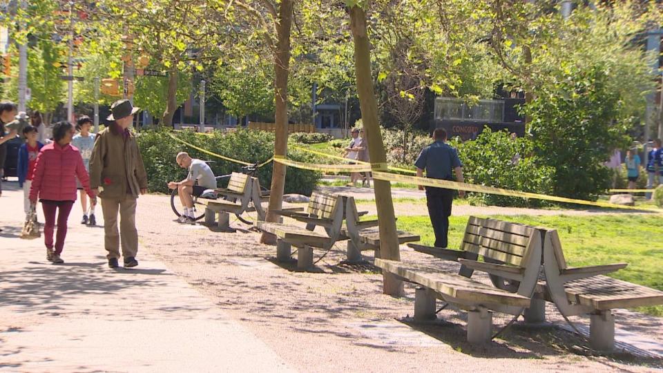 Onlookers gaze at the taped off Hinge Park, located along a busy route by the seawall in Vancouver's Olympic Village. 