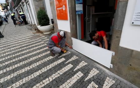 Two workers install a protection board before the arrival of Hurricane Lorenzo in Angra do Heroismo in the Azores islands