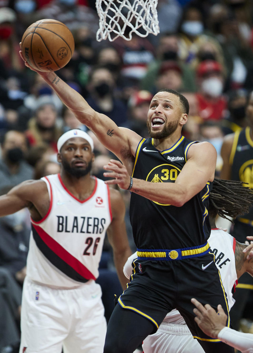 Golden State Warriors guard Stephen Curry, right, shoots in front of Portland Trail Blazers forward Justise Winslow during the first half of an NBA basketball game in Portland, Ore., Thursday, Feb. 24, 2022. (AP Photo/Craig Mitchelldyer)