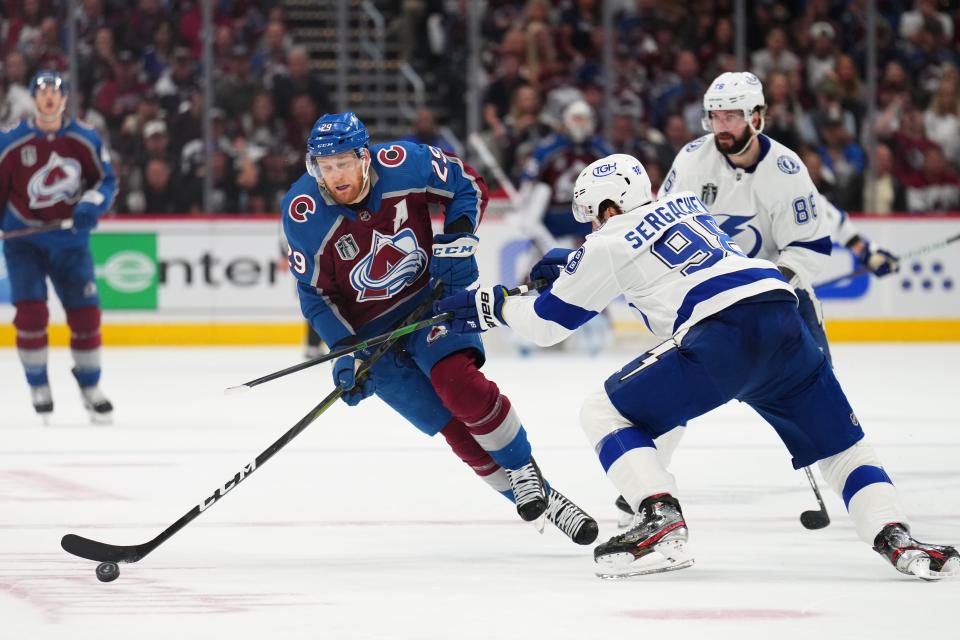 Colorado Avalanche center Nathan MacKinnon (29) moves the puck against Tampa Bay Lightning defenseman Mikhail Sergachev (98) during the second period in Game 5 of the NHL hockey Stanley Cup Final, Friday, June 24, 2022, in Denver. (AP Photo/Jack Dempsey)