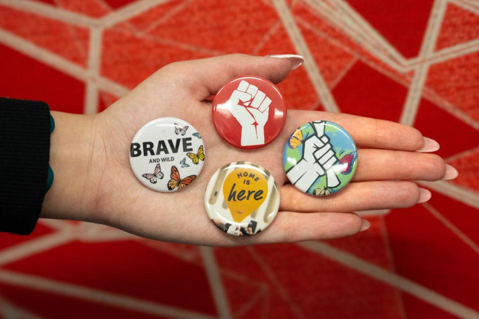 A woman holds buttons made for students at the Dream Success Center.