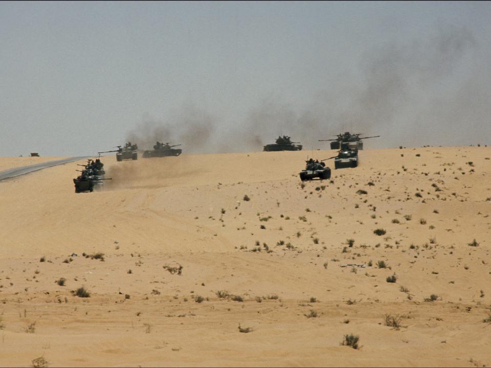 A photo of Tanks rolling over a sandy hill in Sinai.