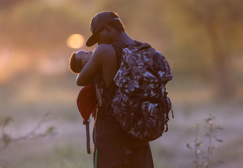 An exhausted Haitian father cradles his son on the Mexican side of the Rio Grande