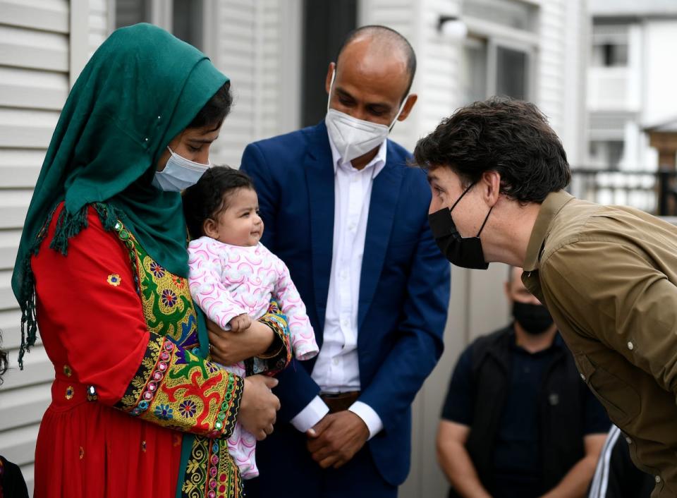 Prime Minister Justin Trudeau gets a smile from Hawa Rahimi, 2 months, as he meets her parents, Obaidullah, right and Arezoo, left, in Ottawa, on Saturday, Oct. 9, 2021. Obaidullah Rahimi worked at the Canadian Embassy in Afghanistan; his family is one of 22 recently resettled Afghan families in the Ottawa area. 