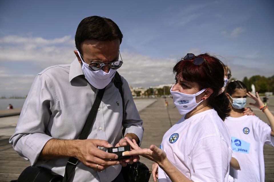 A participant has her oxygen saturation measured, during an event organized by the local medical association, in order to support the use of protective masks, in the northern city of Thessaloniki, Greece, Saturday, Oct. 3, 2020. Lung doctors staged a public demonstration of the benefits of face masks by fast-walking a distance of 2 kilometers (1.25 miles) through the city center aiming to debunk a widely-circulated rumor by anti-mask conspiracy theorists that wearing one left people short of breath. (AP Photo/Giannis Papanikos)