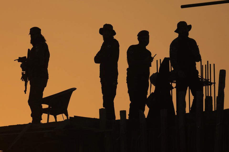 Pakistan police commandos stand guard on a rooftop while they observe the area to ensure the security of the rally of Pakistan's former Prime Minister Imran Khan's 'Pakistan Tehreek-e-Insaf' party, in Rawalpindi, Pakistan, Saturday, Nov. 26, 2022. Khan said Saturday his party was quitting the country's regional and national assemblies, as he made his first public appearance since being wounded in a gun attack earlier this month. (AP Photo/Anjum Naveed)