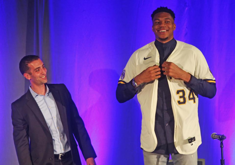 Milwaukee Bucks forward Giannis Antetokounmpo tries on his personal Milwaukee Brewers jersey while Milwaukee President of Baseball Operations, David Stearns watches. It was announced that Antetokounmpo would become an investor in the team on Friday, Aug. 20, 2021 at the American Family Field.