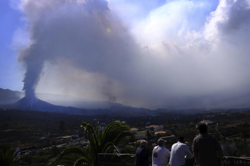 People look towards a volcano as it continues to erupt in El Paso on the canary island of La Palma, Spain, Saturday Oct. 9, 2021. A new lava flow has belched out from the La Palma volcano and it threatens to spread more destruction on the Atlantic Ocean island where molten rock streams have already engulfed over 1,000 buildings. The partial collapse of the volcanic cone overnight sent a new lava stream Saturday heading toward the western shore of the island. (AP Photo/Daniel Roca)
