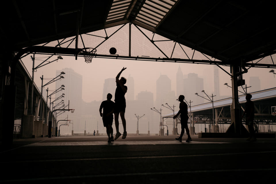 Hazy skies don't keep people from the basketball court at Brooklyn Bridge Park in New York City