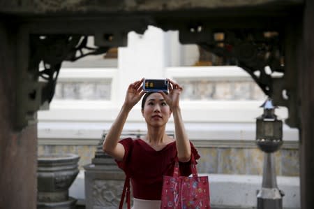 A tourist takes pictures inside a temple in Bangkok Thailand