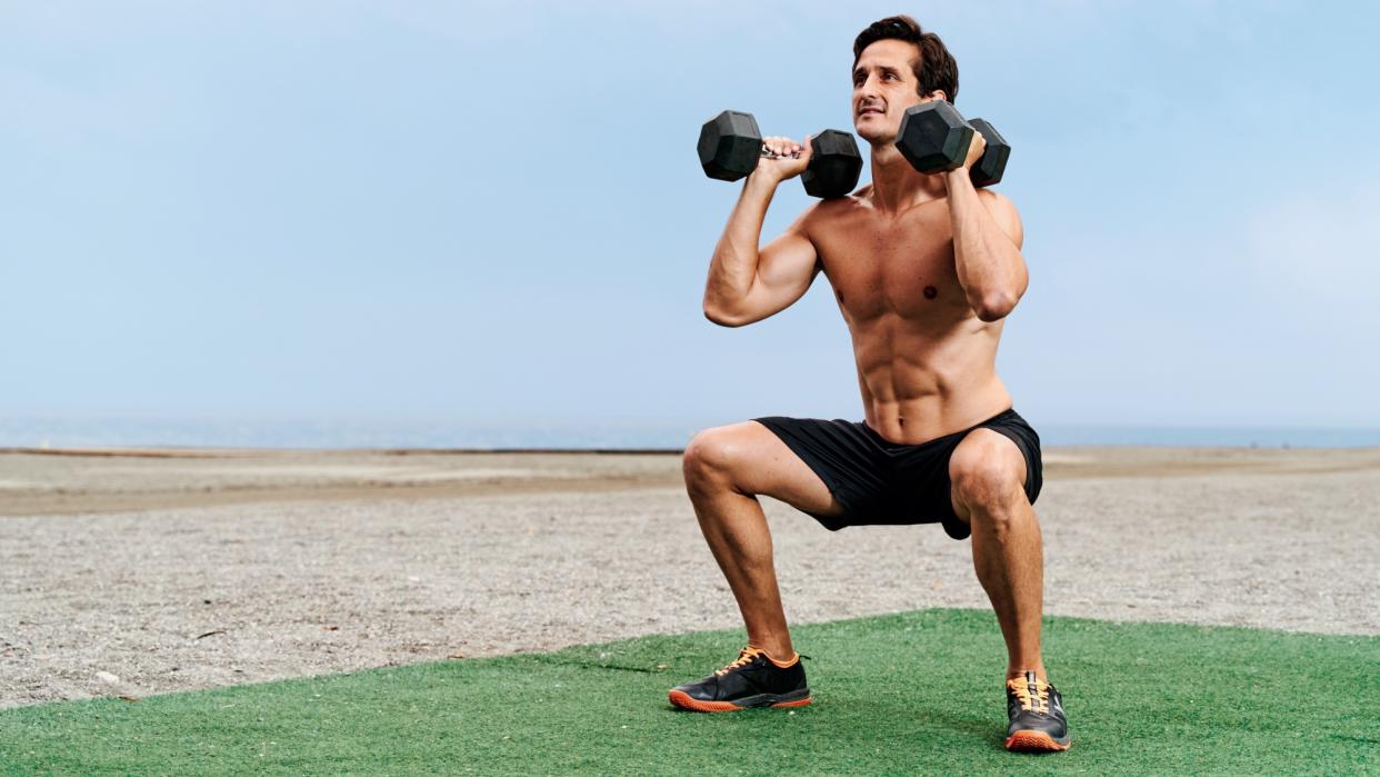  Man doing a squat with two dumbbells . 