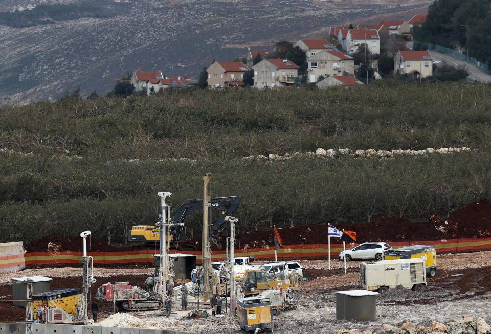 In this Thursday, Dec. 13, 2018 photo, Israeli military equipment works on the Lebanese-Israeli border in front of the Israeli town of Metula, background, near the southern village of Kafr Kila, Lebanon. As Israeli excavators dig into the rocky ground, Lebanese across the frontier gather to watch what Israel calls the Northern Shield operation aimed at destroying attack tunnels built by Hezbollah. But Lebanese soldiers in new camouflaged posts, behind sandbags, or inside abandoned homes underscore the real anxiety that any misstep could lead to a conflagration between the two enemy states that no one seems to want. (AP Photo/Hussein Malla)