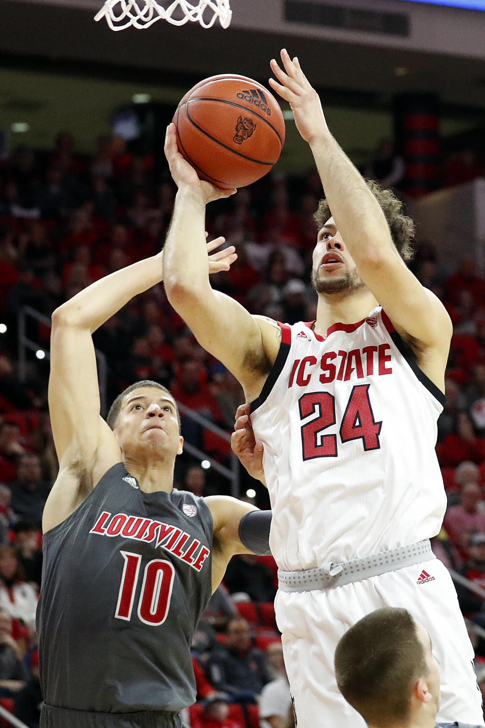 North Carolina State's Devon Daniels (24) drives the ball past Louisville's Samuell Williamson (10) during the first half of an NCAA college basketball game in Raleigh, N.C., Saturday, Feb. 1, 2020. (AP Photo/Karl B DeBlaker)