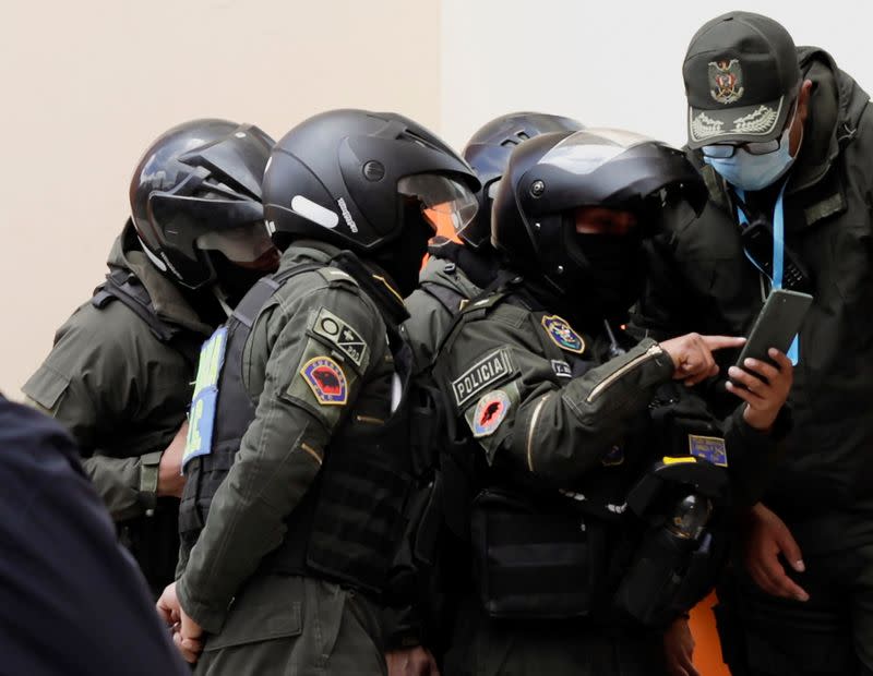 Policías observan la pantalla de un teléfono celular en la Universidad Pública de El Alto (UPEA), donde una baranda metálica de seguridad se rompió y ocho estudiantes cayeron al vacío, in El Alto, Bolivia