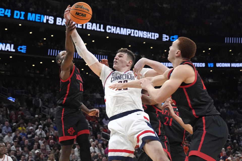 UConn center Donovan Clingan, center, battles for a rebound against San Diego State guard Darrion Trammell, left, and forward Elijah Saunders, right, during the first half of the Sweet 16 college basketball game in the men's NCAA Tournament, Thursday, March 28, 2024, in Boston. (AP Photo/Steven Senne)