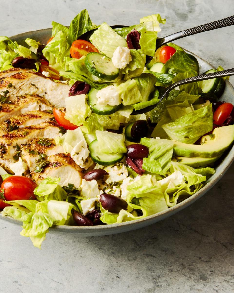 salad topped with sliced grilled chicken, cucumbers, cherry tomatoes, olives, and feta