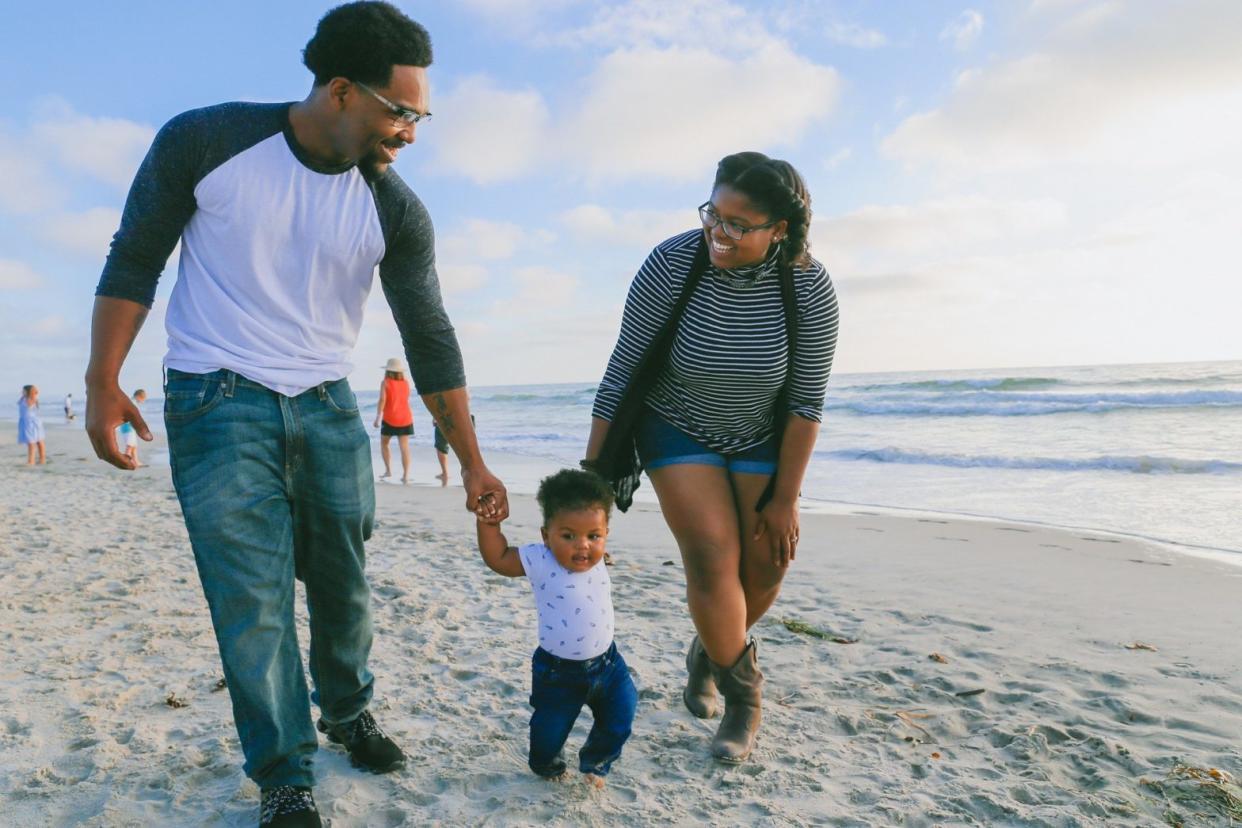 Black family with toddler walking along the beach - Unique vacation spots for families