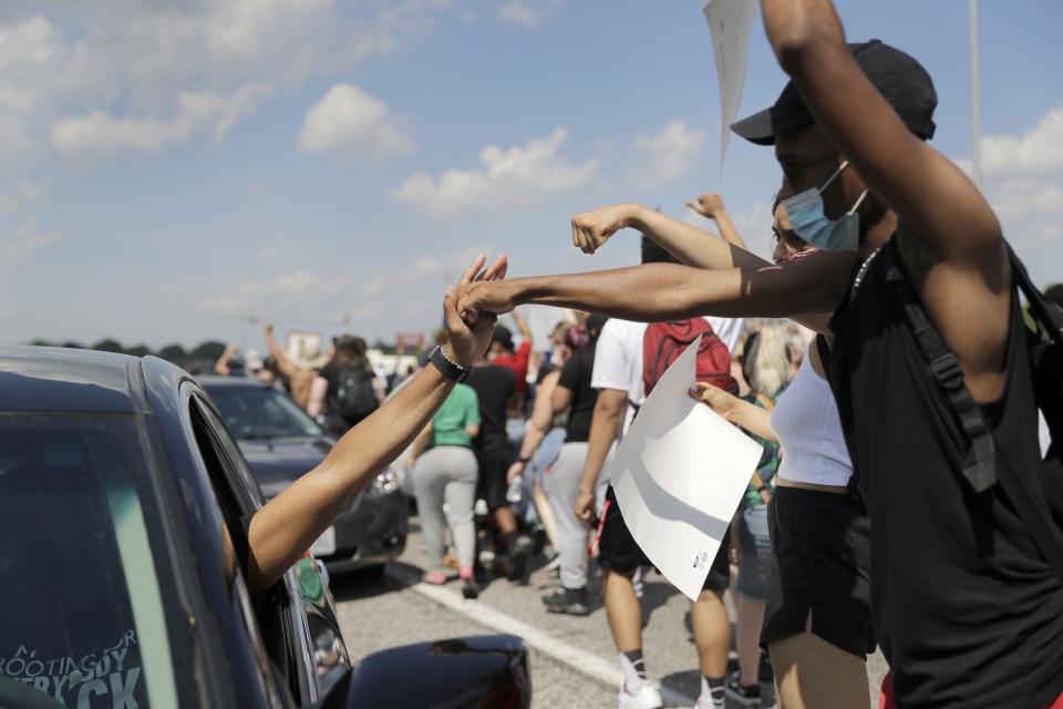 A motorist gets a fist bump from a passing protester as a demonstration shuts down a highway Wednesday in St. Charles, Mo.