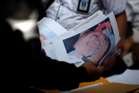 Indonesian Disaster Victim Identification (DVI) officer holds pictures and identity documents of passengers on the crashed Lion Air flight JT610, at Bhayangkara R. Said Sukanto hospital in Jakarta, Indonesia, October 30, 2018. REUTERS/Willy Kurniawan