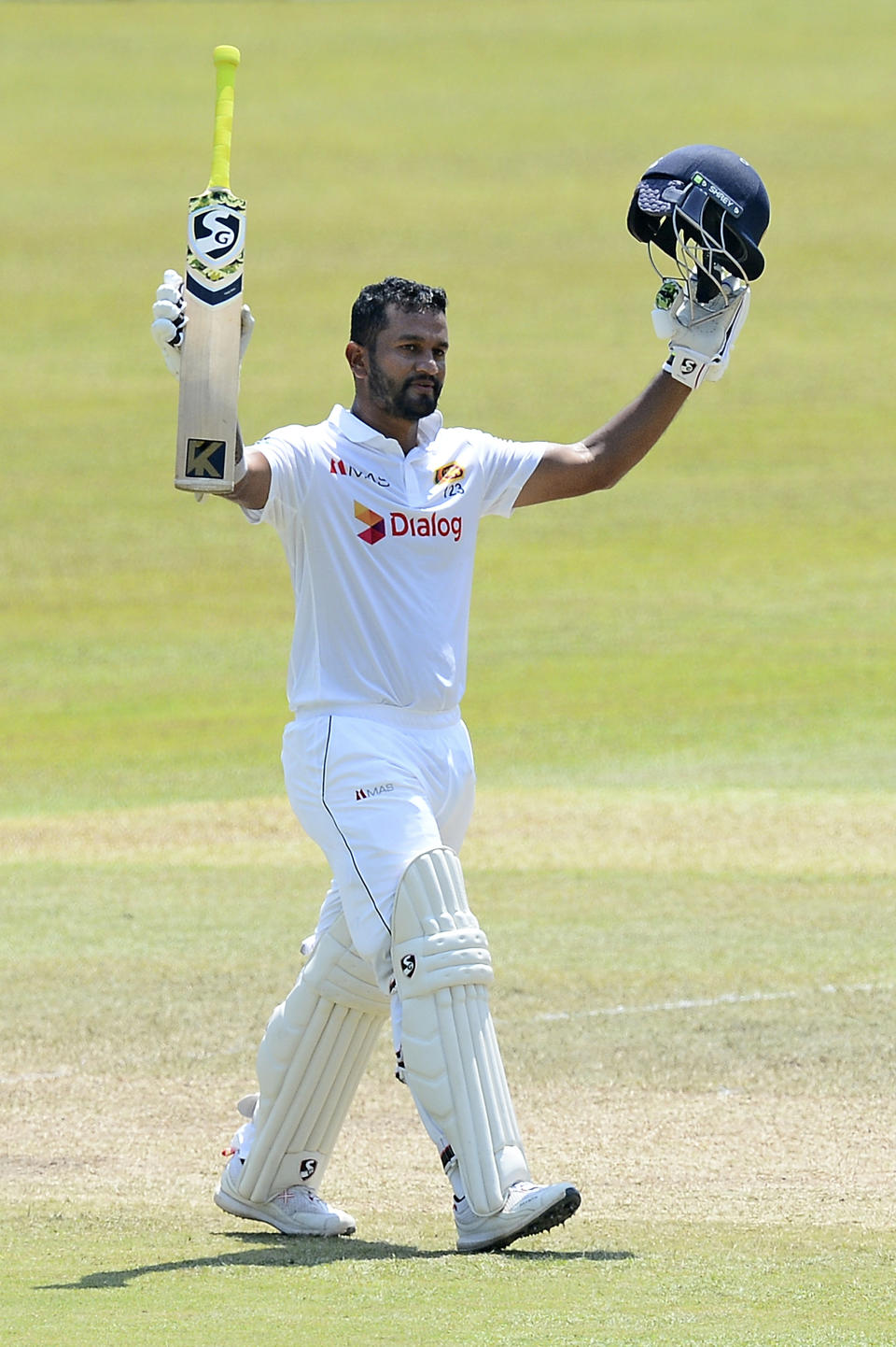 Sri Lankan captain Dimuth Karunaratne raises his bat as he celebrates scoring a century during the fourth day of the first test cricket match between Sri Lanka and Bangladesh in Pallekele, Sri Lanka, Saturday, April 24, 2021.( AP Photo/Sameera Peiris)