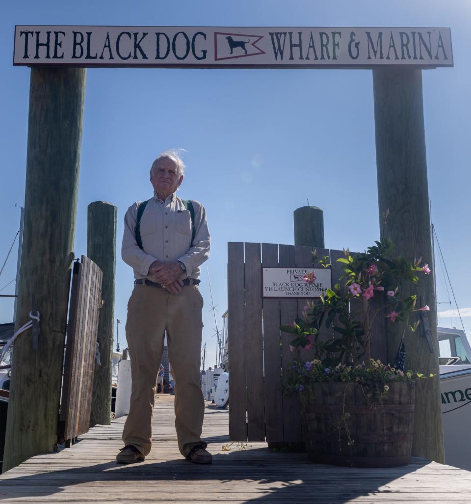 Captain Bob Douglas, 90, stands in front of The Black Dog Wharf & Marina sign in Vineyard Haven.