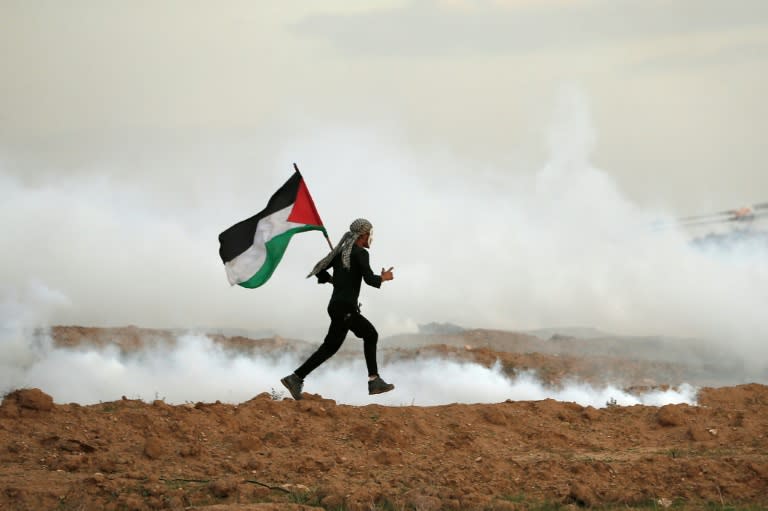 A Palestinian man runs as he holds a flag during a protest, east of Gaza City near the Israeli border on November 16, 2018