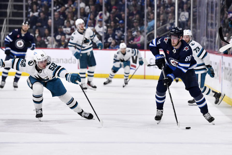 Winnipeg Jets' Pierre-Luc Dubois (80) carries the puck past San Jose Sharks' Tristen Robins (52) during second-period NHL hockey game action in Winnipeg, Manitoba, Monday April 10, 2023. (Fred Greenslade/The Canadian Press via AP)