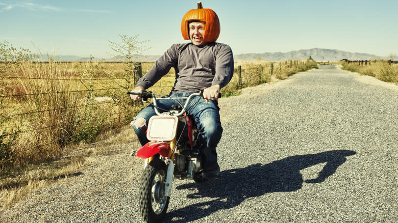 motorcyle rider wears pumpkin helmet