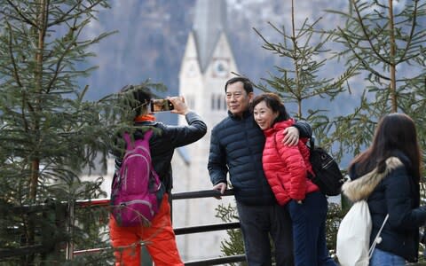 Tourists take photos in the town center on January 16, 2019 in Hallstatt, Austria. Hallstatt, known for its picturesque beauty and its location at the base of a mountain on Hallstatter See lake, is struggling to cope with large influxes of tourists throughout the year. - Credit: Getty/Andreas Gebert&nbsp;