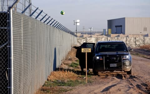 A private security guard throws a soccer ball back inside the Tornillo detention camp - Credit: AP