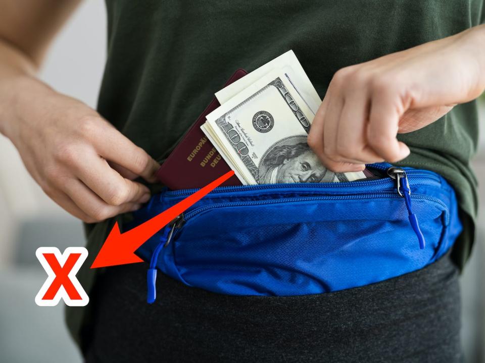 A person puts $100 bills into their fanny pack.