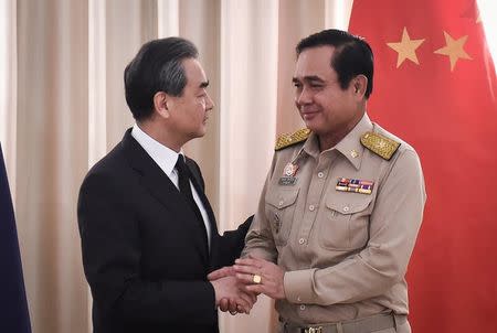 Chinese Foreign Minister Wang Yi (L) shakes hands with Thai Prime Minister Prayuth Chan-O-Cha (R) at Government House in Bangkok, Thailand July 24, 2017. REUTERS/Lillian Suwanrumpha/Pool