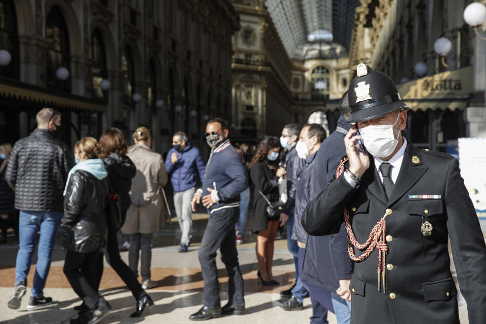 A traffic policeman talks on the phone at the Vittorio Emanuele II arcade, in Milan, Italy, Friday, Oct. 16, 2020. Italian health officials have declared the country in an "acute phase" after the country set records for new daily cases higher than even during the March-April peak, when the death toll surged well over 900 in one 24-hour period. Regions have urged the government to allow distance learning for the upper grades of high school, to take pressure off public transport which remains a major concern due to crowding. (AP Photo/Luca Bruno)